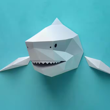 Grijze Assembli 3D-puzzel haai op blauwe muur, wanddecoratie met witte tanden en zwarte ogen.