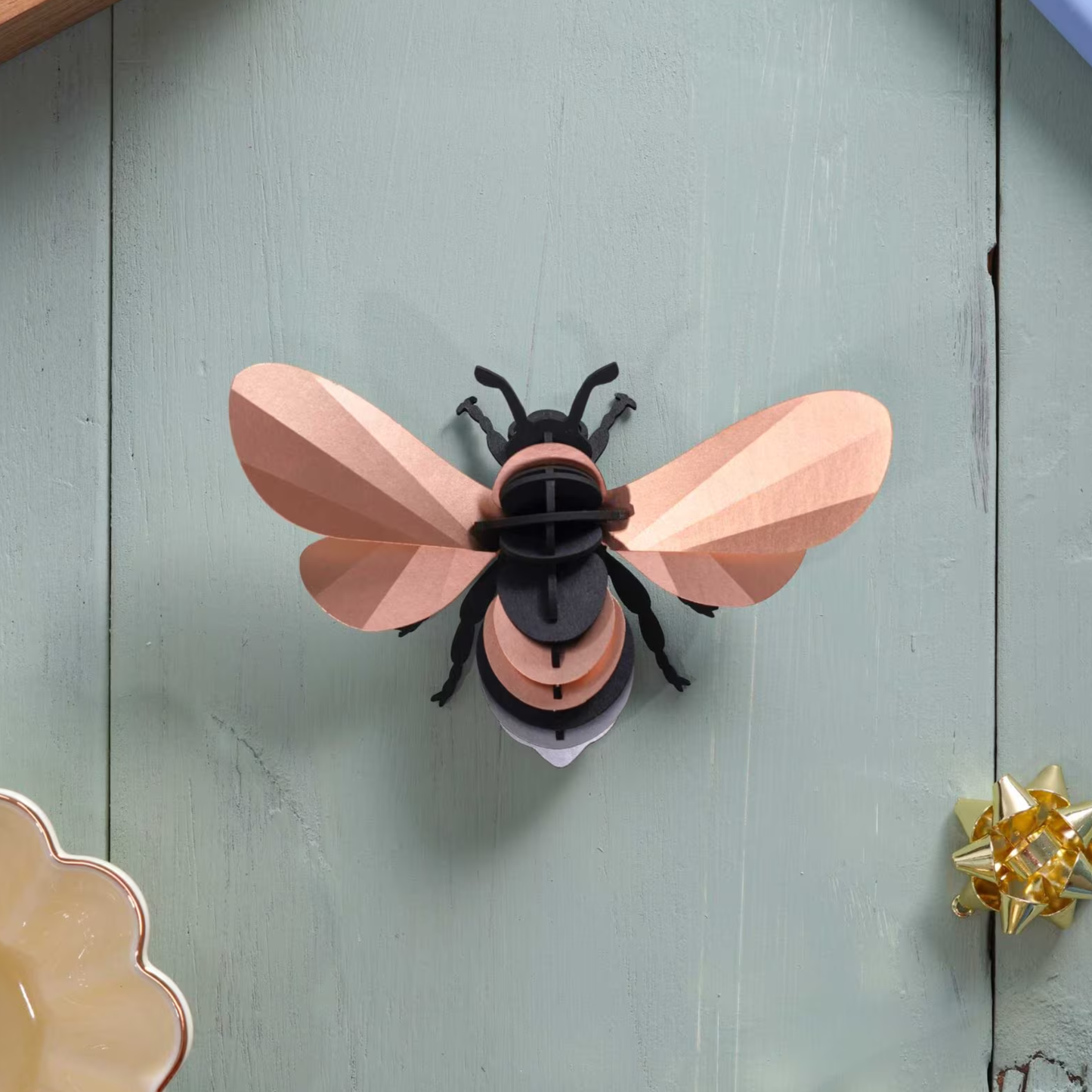 Assembli papieren hommel 3D-puzzel in rose goud liggend op houten tafel
