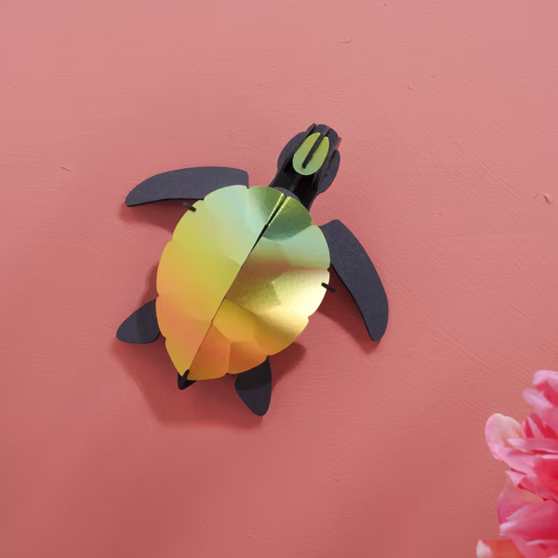Assembli papieren zeeschildpad baby 3D-puzzel mango groen als wanddecoratie op een roze muur - compacte papercraft van 10,5 x 10 cm.