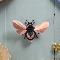 Assembli papieren hommel 3D-puzzel in rose goud  liggend op houten tafel