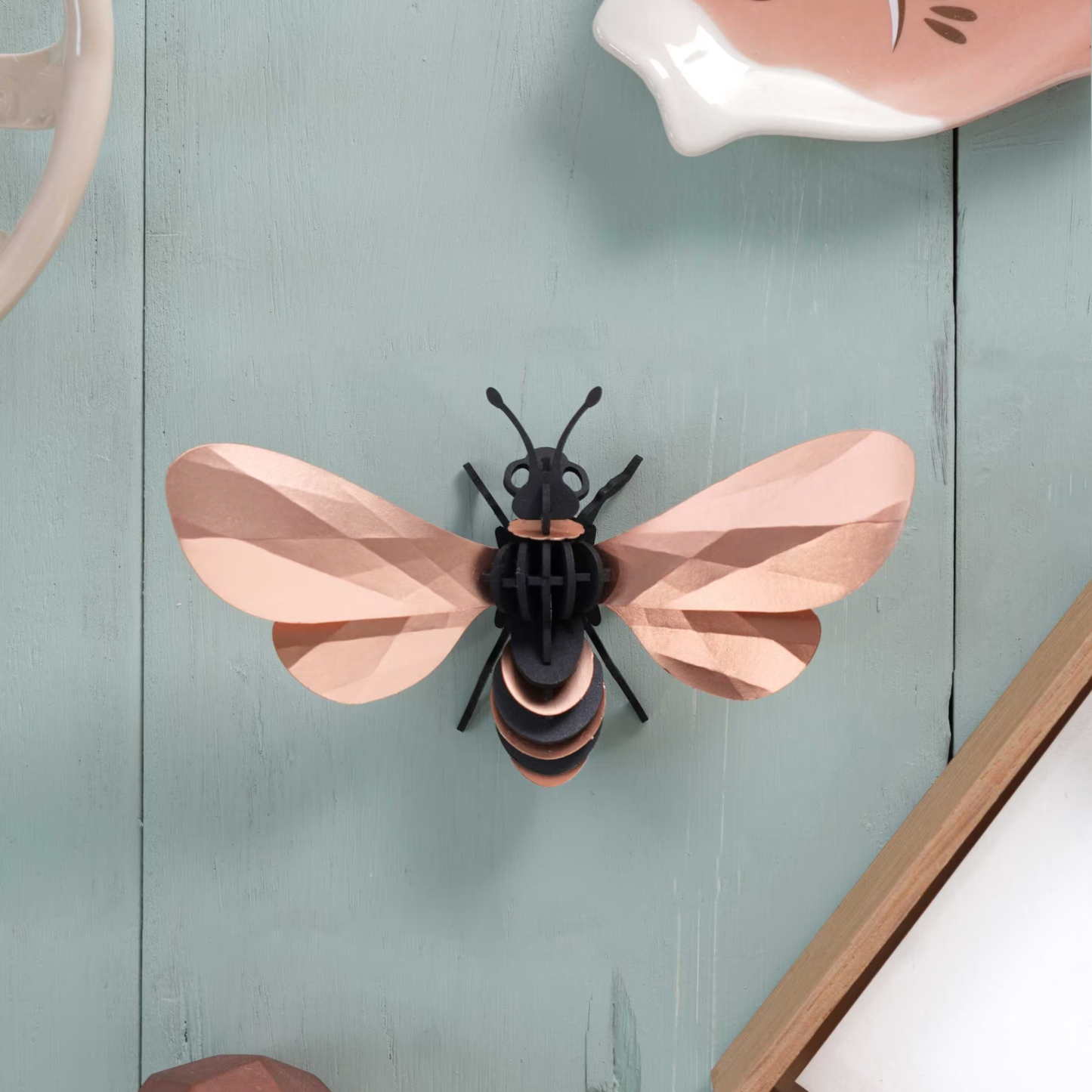 Assembli 3D-puzzel honingbij van rose goud papier aan een muur