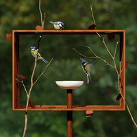 Vogels bij de Frederik Roijé Framed Feeder, een vogelvoederhuis van cortenstaal in de tuin