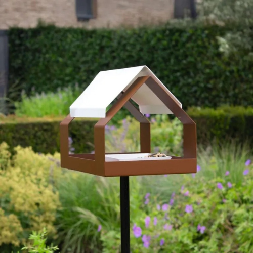 Hey! Das Scheunen-Vogelhäuschen, braun mit weißen Akzenten, steht auf einer Stange.