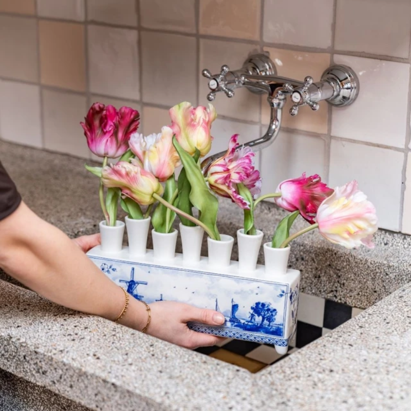 Delfts blauwe tulpenvaas met molen, gevuld met kleurrijke tulpen onder kraan