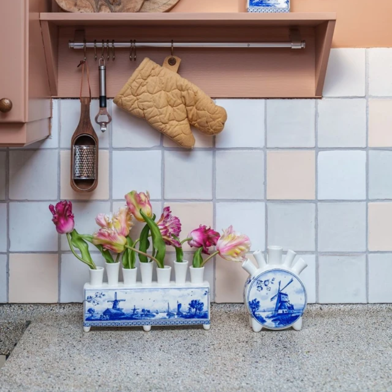 Delfts blauwe tulpenvaas met molen, gevuld met kleurrijke tulpen op het aanrecht