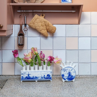Delfts blauwe tulpenvaas met molen, gevuld met kleurrijke tulpen op het aanrecht